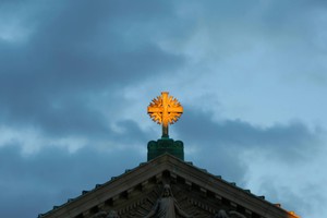 The cross atop St. Joseph Memorial Chapel illuminated by the sun.