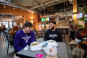 Two male students talk while talking to each other at a table in a city cafe.